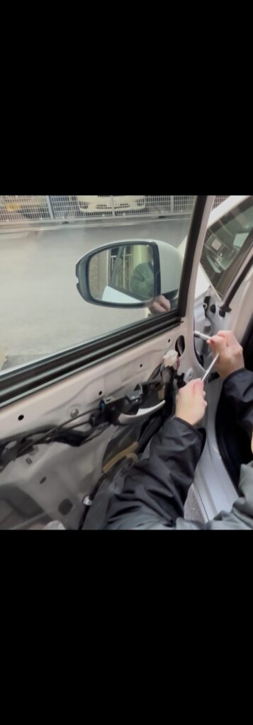 中古で用意したドアミラーを車へ取り付けて交換している作業の様子