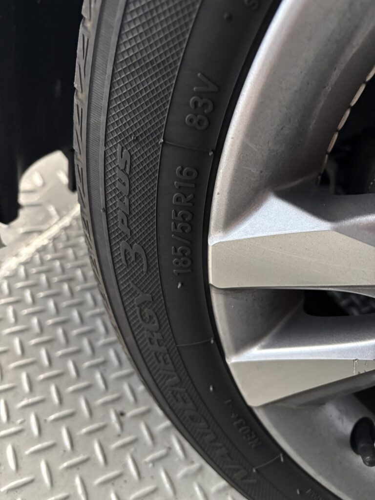 タイヤ側面の185/55R16というサイズ表示を確認している様子