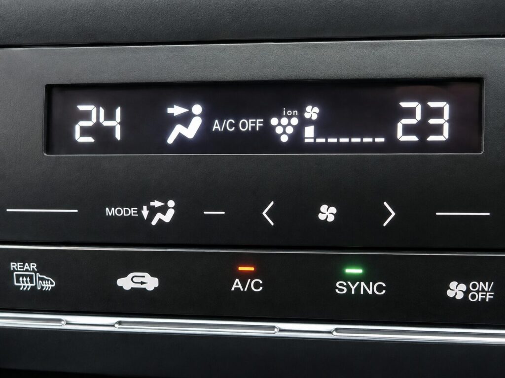 車のエアコン操作パネルに表示された設定温度や送風モード、A/Cの作動状況を確認している様子。