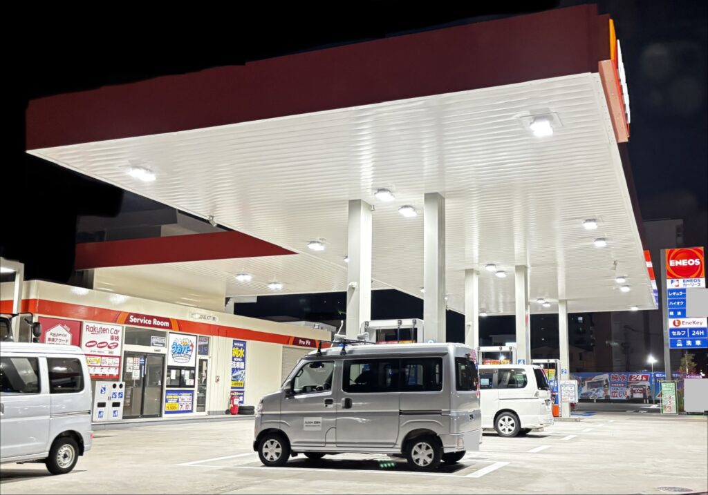 夜間のENEOSガソリンスタンドで複数の車が給油スペースに停車している様子