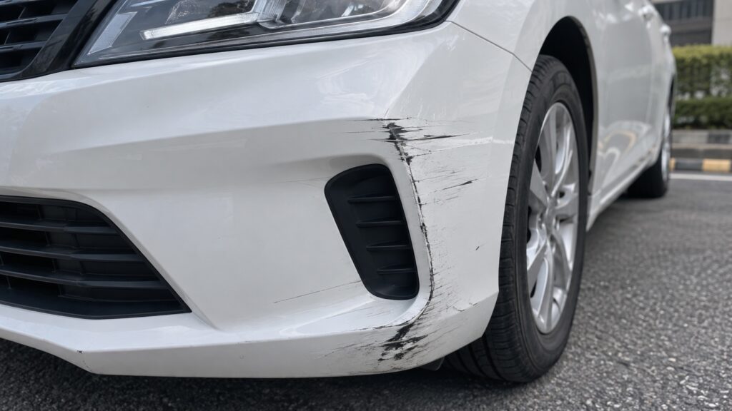 白い車のフロントバンパーに付いた擦り傷と修理が必要な状態