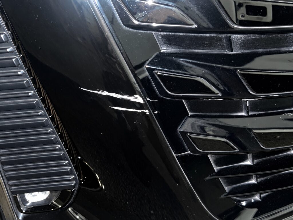 黒い車のフロント部分についた白い擦り傷